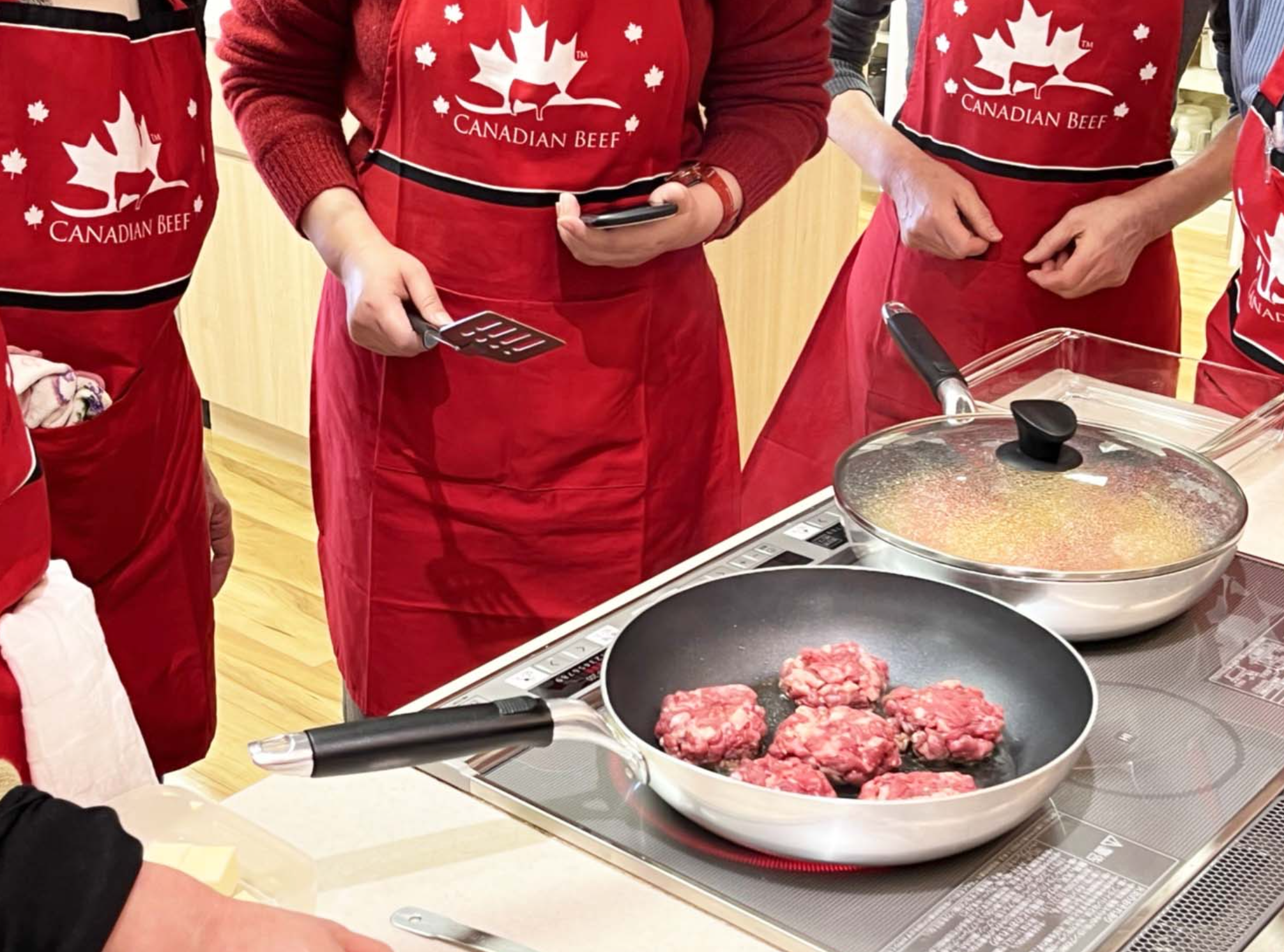 カナダで学んだ“食べることの自由”をイメージさせる写真。カナディアンビーフのエプロンをしながら、スクール生が「登志子のキッチン」料理教室で調理している様子。